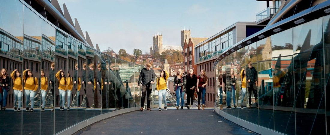 University students walking across a bridge.